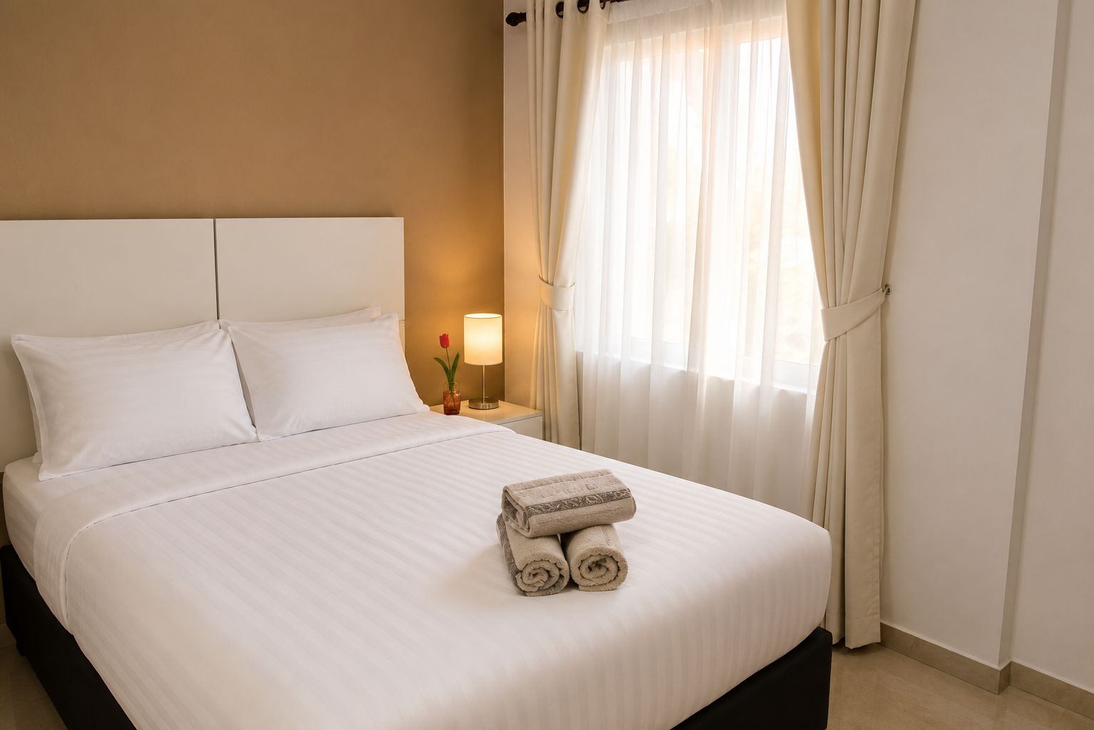 Clean hostel suite with a made double bed, flat-screen TV and air conditioning
